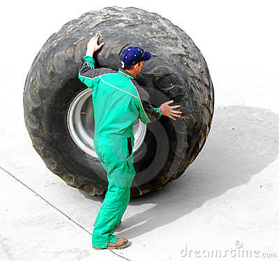 man-rolling-huge-truck-wheel-thumb2588832.jpg