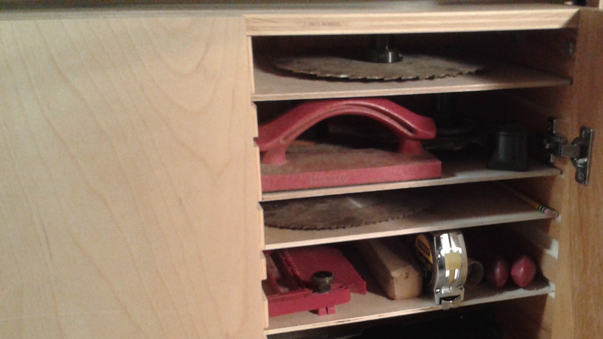 Right side cabinet with saw blades, lower safety guard, and various other small regularly used items.