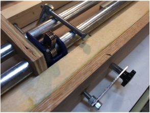 Rod coupling on other end of knob contacts bench side and is tensioned by the pipe clamp springs.